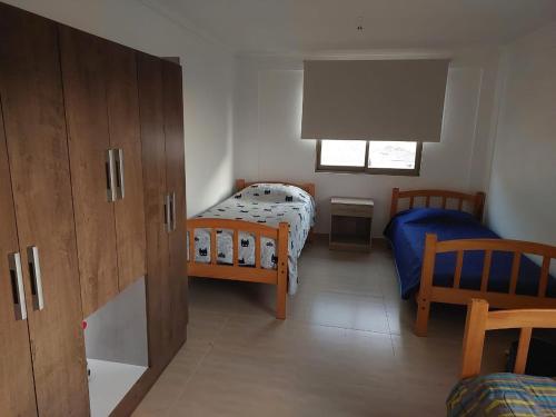 Habitación pequeña con 2 camas y ventana en Casa Rural Poblado de Acha Arica en Arica