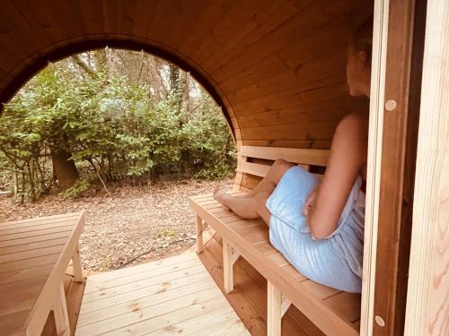 a woman is sitting in a dog house at Wellness in the Woods - 4p TinyHouse met privé sauna & hottub in Diessen