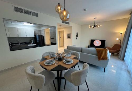 een woonkamer met een tafel en stoelen en een bank bij EasyGo - Polo Residence 1 Bedroom Community View in Dubai