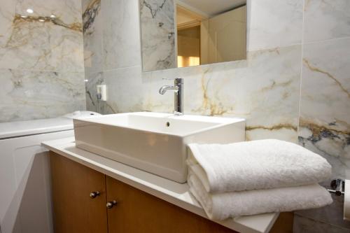 Baño blanco con lavabo y espejo en KATAKIS LUXURY APARTMENT en La Canea