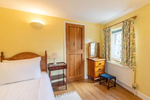 a bedroom with a bed and a table and a window at Corner Cottage - The Pink House in Southwold