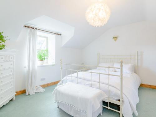 een witte slaapkamer met een bed en een kroonluchter bij 2 Bed in Alnwick 78643 in Edlingham