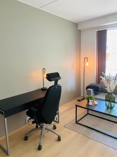 een kamer met een bureau, een stoel en een bank bij Leilighet ved Tønsberg Brygge in Tønsberg