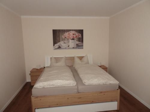 Una cama en una habitación con un jarrón de flores en FeWo Kästner Pirna, en Pirna