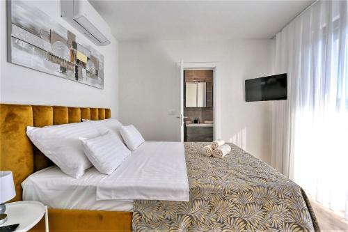 Cette chambre comprend un lit avec des draps blancs et une télévision. dans l'établissement Villa Frantin, à Privlaka