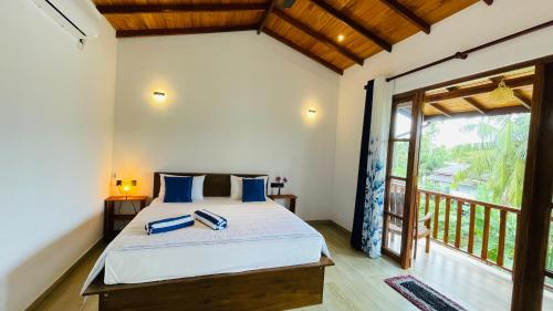 1 dormitorio con 1 cama con almohadas azules y balcón en The Point Mirissa en Mirissa