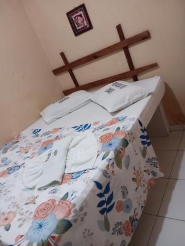 1 cama con colcha floral y almohadas en Pousada Dos Sonhos e Restaurante en Tacima