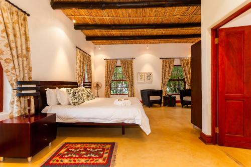 a bedroom with a large white bed and two windows at Nabygelegen Gate house in Bainʼs Kloof