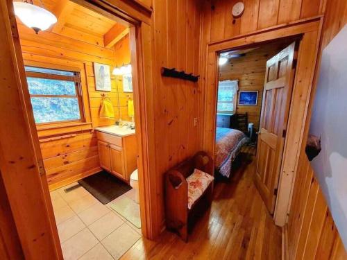 baño pequeño con cama y lavamanos en una cabaña de madera en Little Wolf Cabin, en Maggie Valley