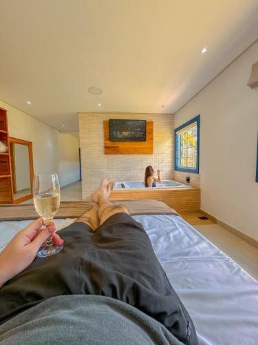 a man laying on a bed with a glass of wine at Hotel Pontal de Tiradentes in Tiradentes