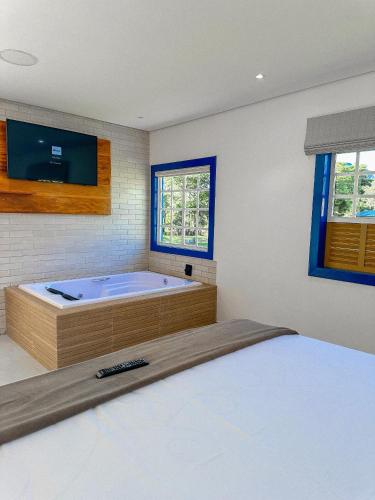 a bedroom with a tub with a tv and a bed at Hotel Pontal de Tiradentes in Tiradentes
