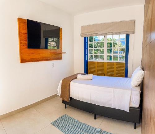 a bedroom with a bed and a window at Hotel Pontal de Tiradentes in Tiradentes