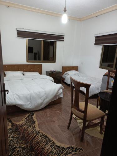 um quarto com 2 camas, uma cadeira e uma mesa em Jerash Ruins Hotel em Gérasa