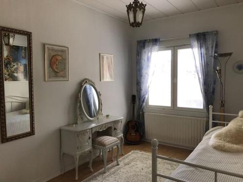 1 dormitorio con espejo y 1 cama con silla en Romanttinen Retrokaksio, en Oulu