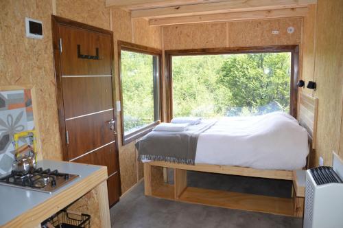 ein Schlafzimmer in einem winzigen Haus mit einem Bett und einem Fenster in der Unterkunft Cerro Electrico - Off The Grid Tiny Houses in El Chalten