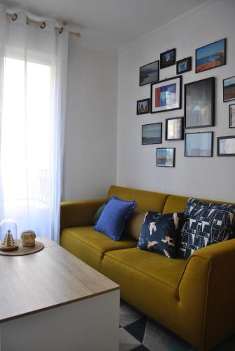 uma sala de estar com um sofá amarelo e quadros na parede em Cocon en centre-ville em Brest