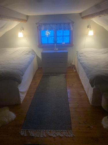 two beds in a room with a window and a rug at Mysig stuga i vemdalssskalet in Vemdalen