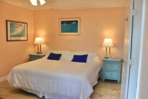 a bedroom with a large white bed with two blue tables at Sunset Cove Beach Resort in Key Largo