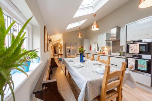 a dining room with a table and chairs and a kitchen at The Pottage in Hoxne