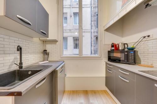 une cuisine avec un évier et un micro-ondes dans l'établissement Le Bon Pasteur - Joli T2 Place de la Victoire, à Bordeaux