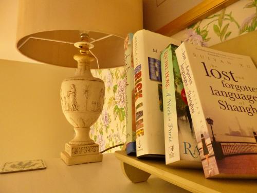 a lamp sitting on top of a shelf with books at Finest Retreats - No 2 Meynell Mews in Breedon on the Hill