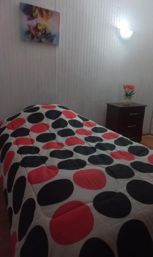 a bed with a red black and white comforter at Health & Wisdom in Antofagasta