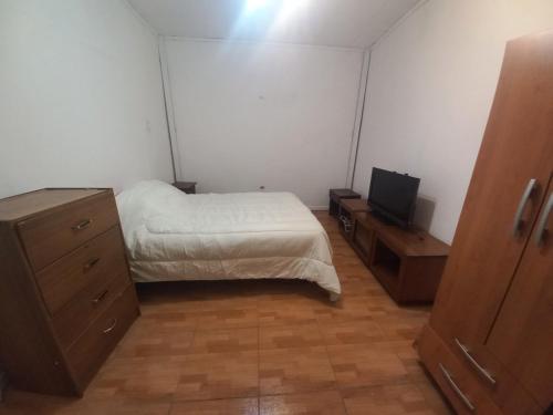 a bedroom with a bed and a dresser and a tv at Health & Wisdom in Antofagasta