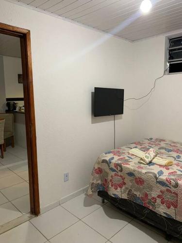 um quarto com uma cama e uma televisão na parede em Casa próximo ao aeroporto em Rio Largo