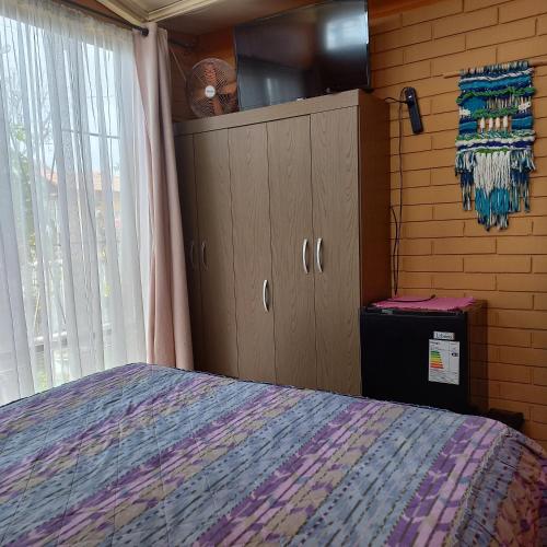a bedroom with a bed and cabinets and a window at Hostal Los Nogales in Coquimbo