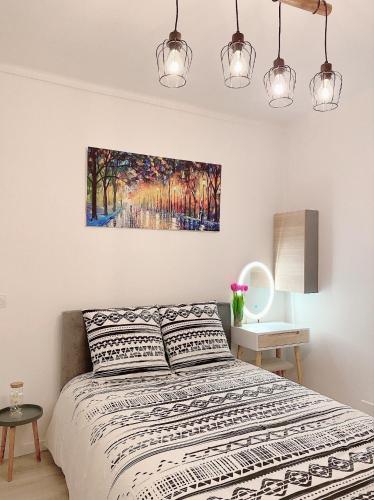 ein Schlafzimmer mit einem Bett und einem Gemälde an der Wand in der Unterkunft Charmant et moderne de L’Hay in LʼHay-les-Roses