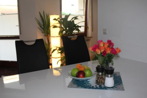 a table with a bowl of fruit and a bowl of apples and flowers at Ferienwohnung Novotny in Lörrach