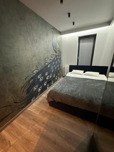 Beautiful Apartment Tarasy Wiślane Free GARAGE في كراكوف: غرفة نوم مع سرير مع لوحة طاووس على الحائط