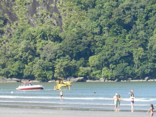 a group of people on a beach with a boat in the water at Pousada Acqua Bella PISCINA CLIMATIZADA in Bertioga
