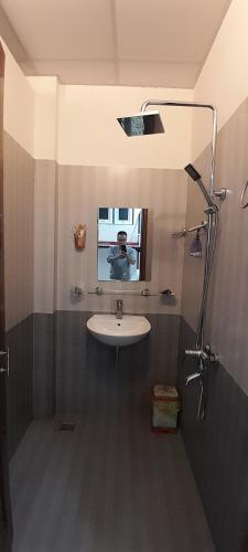 a man taking a picture of a bathroom with a sink at Khách sạn 68 ĐỒNG HẢI in Dong Hoi