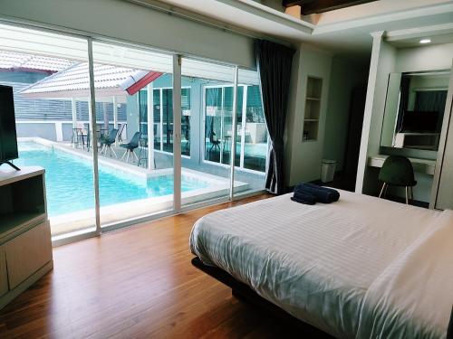 a bedroom with a bed and a view of a pool at I am pool villa Pattaya no 5 in Ban Nong Phlap