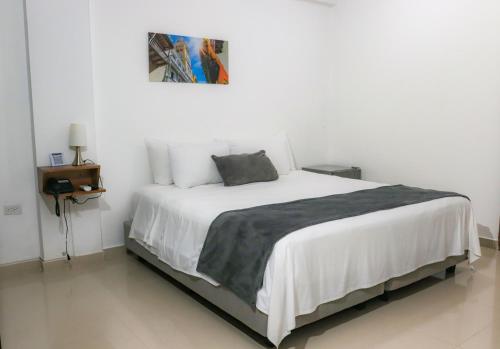 a bedroom with a large white bed with a picture on the wall at Hotel El Marqués De Manga in Cartagena de Indias