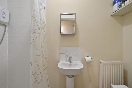 een witte badkamer met een wastafel en een spiegel bij LiveStay - One Bedroom Studio Near The Beach in Southend-on-Sea