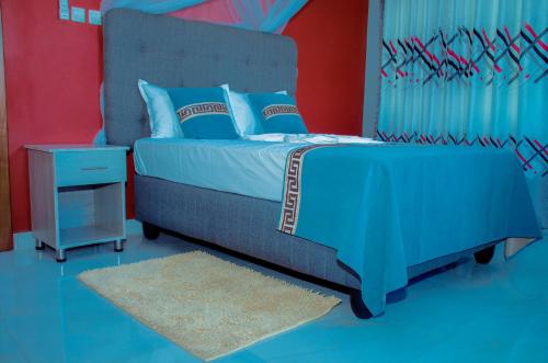 布松布拉的住宿－Kinindo Light Hotel，一间卧室设有蓝色和红色的墙壁。