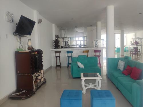 a living room with two blue couches and a kitchen at Hospedaje El Candelabro de Paracas in Paracas