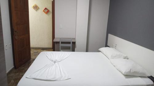 1 dormitorio con 1 cama con sábanas y almohadas blancas en POUSADA TAHITI, en Pasto da Mata