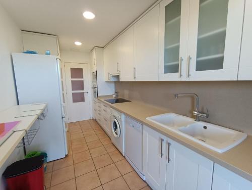 La cuisine est équipée d'un évier et d'un réfrigérateur blanc. dans l'établissement Apartamento con solárium en Marina Sant Jordi (MSJ81), à Calafat