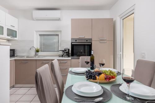 a kitchen with a table with a bowl of fruit and wine glasses at Apartment City flower in Rijeka