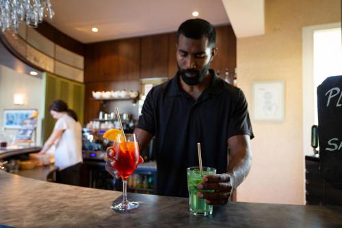 a man with a beard standing at a bar with a drink at Hôtel Miléade Le Domaine de la Blairie - Saumur in Saint-Martin-de-la-Place