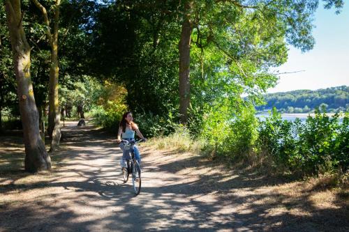 a woman riding a bike on a path near a lake at Hôtel Miléade Le Domaine de la Blairie - Saumur in Saint-Martin-de-la-Place