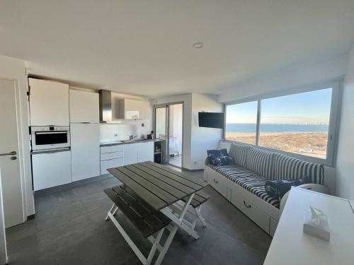 une cuisine et un salon avec une table et un canapé dans l'établissement Bel appartement P2 climatisé vue sur mer pour 2/4 pers avec terrasse et parking, au Grau-du-Roi