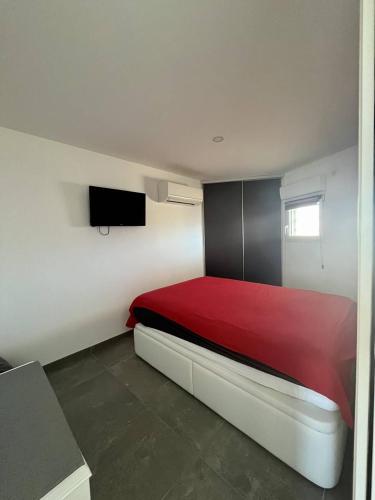 - une chambre avec un lit rouge et une télévision à écran plat dans l'établissement Bel appartement P2 climatisé vue sur mer pour 2/4 pers avec terrasse et parking, au Grau-du-Roi