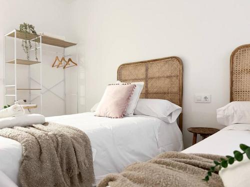 a bedroom with two beds with white sheets and pink pillows at Apartamentos Gredos 201 in Jaraiz de la Vera