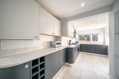 a kitchen with white cabinets and gray counters at Enjoy a Luxury & Peaceful Home in Loughton, Essex in Loughton