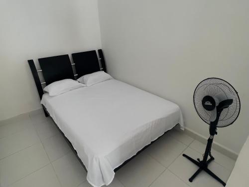 a bedroom with a white bed and a fan at Loft Vacacional in Mariquita