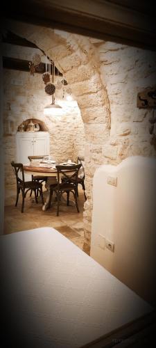 a dining room with a table and a stone wall at Trullo del Vescovo in Alberobello